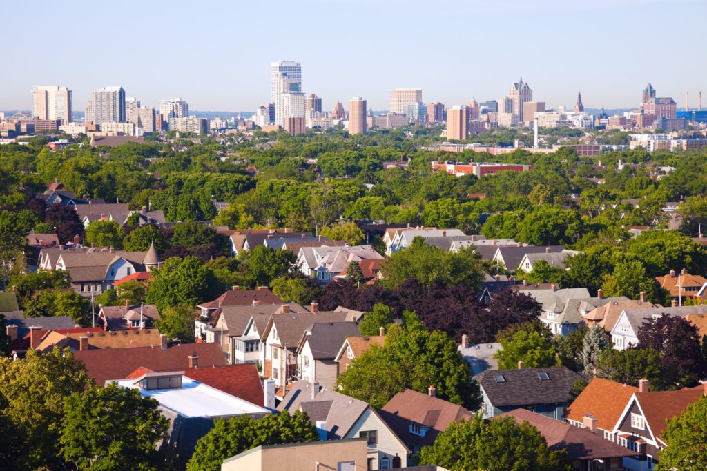 Aerial view of Brookfield residential neighborhood with tree-lined streets and downtown Milwaukee skyline in the background on a clear day.
