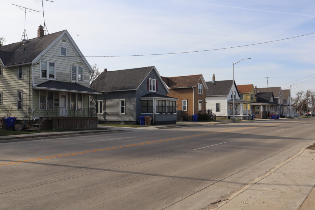 Row of older single-family homes along a quiet residential street in Kenosha, Wisconsin, on a clear day.