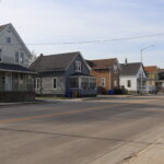 Row of older single-family homes along a quiet residential street in Kenosha, Wisconsin, on a clear day.