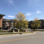 Modern apartment complex in New Berlin with parked cars, autumn trees, and clear blue skies.