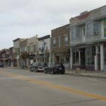 Downtown street view in West Allis, Wisconsin, featuring local shops, parked cars, and overcast skies.