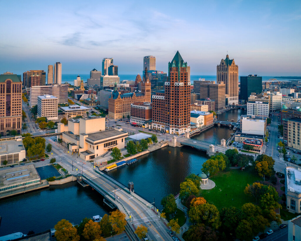 Aerial view of downtown Milwaukee with skyscrapers, the Milwaukee River, and surrounding bridges during early morning light.