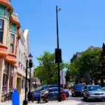 Colorful historic buildings and small businesses line a lively street in downtown Waukesha, Wisconsin, under a bright blue sky.