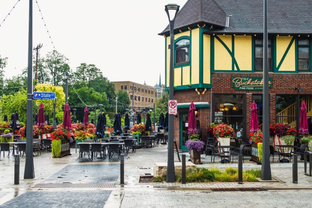 Outdoor dining area with colorful flowers and umbrellas outside Buckatabon restaurant on W. State Street in Wauwatosa, Wisconsin.