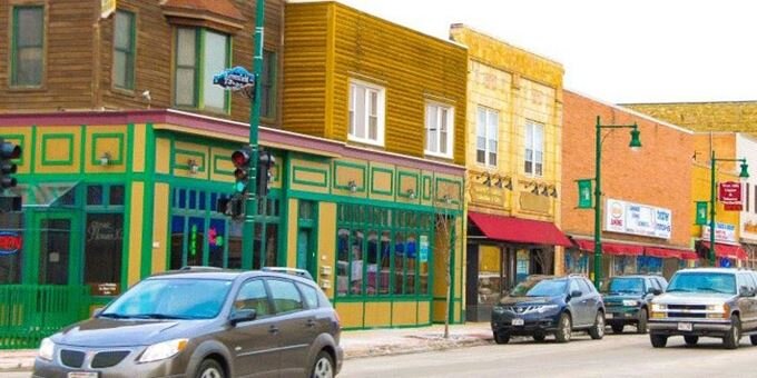 Colorful storefronts and parked cars along a busy street in downtown West Allis, Wisconsin.