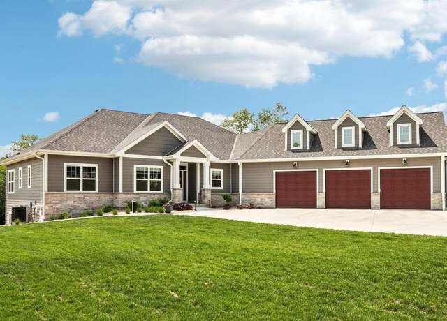 Modern single-story home with large lawn and three red garage doors.
