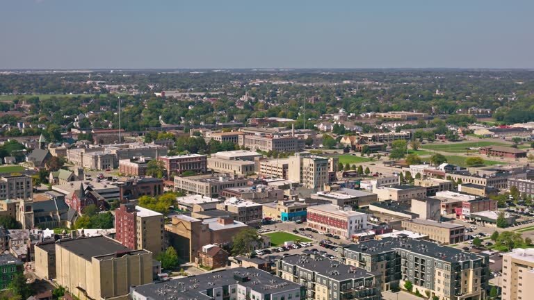Aerial view of downtown Kenosha, Wisconsin, showcasing mid-rise buildings, residential areas, and green spaces under a clear blue sky.