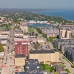 Aerial view of downtown Kenosha, Wisconsin, showing buildings, streets, and Lake Michigan in the background on a clear day