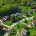 Aerial view of a quiet suburban neighborhood in Brookfield with curved streets, single-family homes, green lawns, and surrounding trees.