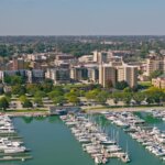 Aerial view of downtown Kenosha, Wisconsin with a marina full of boats in the foreground and city buildings surrounded by trees in the background.