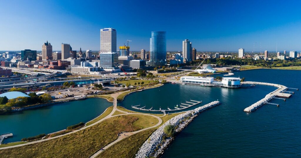 Aerial view of downtown Milwaukee, Wisconsin, showcasing the lakefront, marina, and city skyline under clear blue skies.