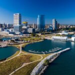 Aerial view of downtown Milwaukee, Wisconsin, showcasing the lakefront, marina, and city skyline under clear blue skies.