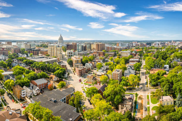 Aerial view of downtown Madison, Wisconsin, featuring the State Capitol building and tree-lined streets on a bright, sunny day.