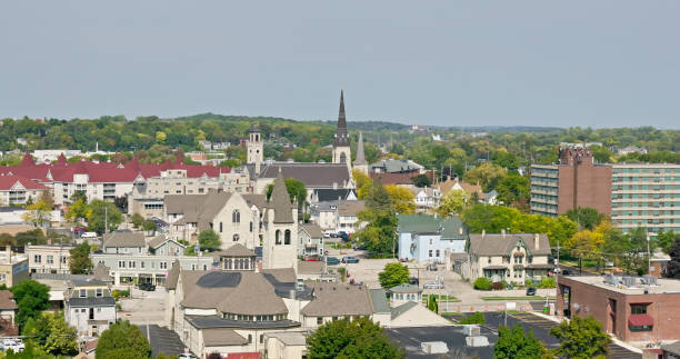 Aerial view of downtown Waukesha, Wisconsin, featuring historic churches, residential buildings, and lush greenery under a clear sky.