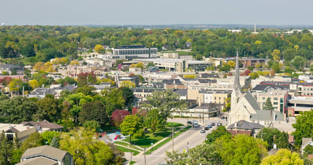 Aerial view of downtown Waukesha, Wisconsin, showcasing historic buildings, a church, and tree-lined streets during spring.