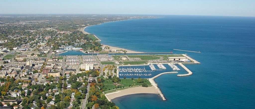 Aerial view of Kenosha, WI, showing the harbor, beach, and Lake Michigan shoreline on a clear day.