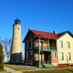 Historic Southport Lighthouse and Keeper’s House in Kenosha, Wisconsin, with clear blue sky and American flag in view.