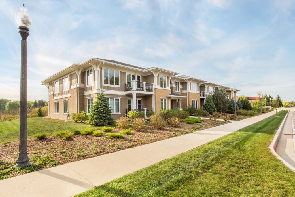 Modern two-story apartment building with landscaped greenery and a clear blue sky in Brookfield, WI.