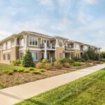 Modern two-story apartment building with landscaped greenery and a clear blue sky in Brookfield, WI.