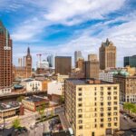 Downtown Milwaukee skyline featuring historic and modern buildings under a partly cloudy sky.