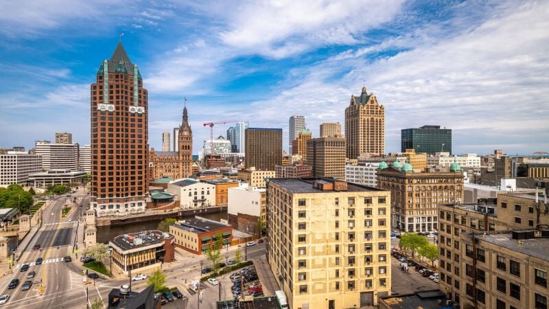 Downtown Milwaukee skyline featuring historic and modern buildings under a partly cloudy sky.