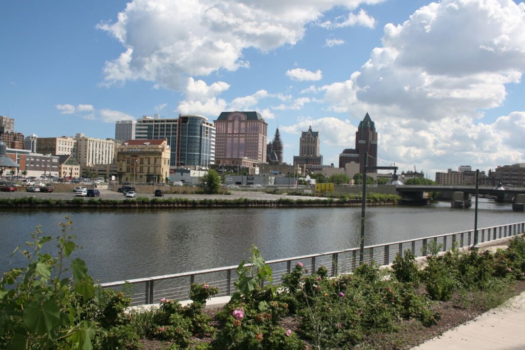 Downtown Milwaukee skyline with riverfront view under a partly cloudy sky.