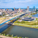 Aerial view of downtown Milwaukee, Wisconsin featuring the Hoan Bridge, waterfront parks, and city skyline on a clear day.