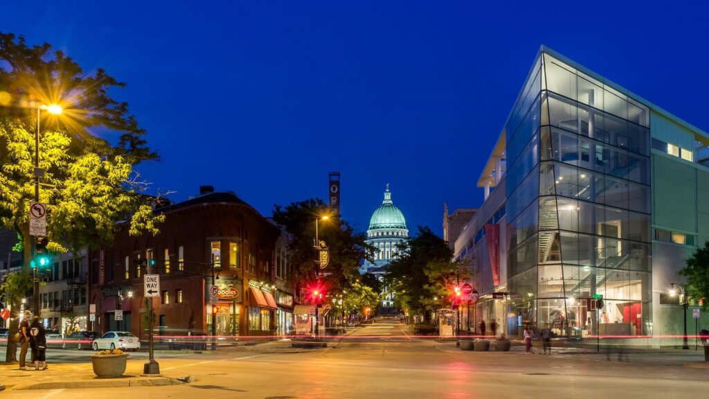Downtown Madison at night with the Wisconsin State Capitol illuminated in the background and the Overture Center on the right.