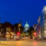 Downtown Madison at night with the Wisconsin State Capitol illuminated in the background and the Overture Center on the right.