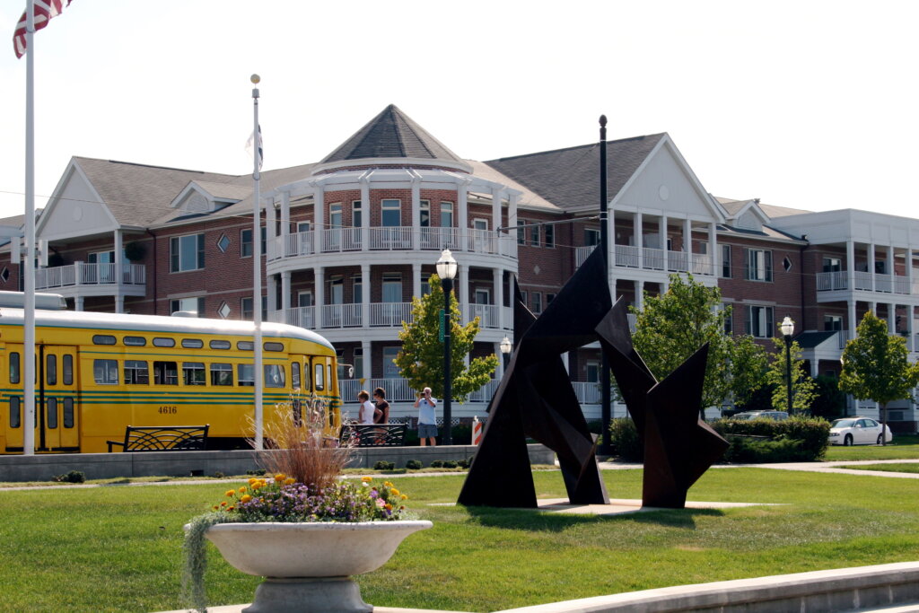 Modern apartment buildings and public art near a yellow streetcar at HarborPark in Kenosha, Wisconsin.