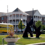 Modern apartment buildings and public art near a yellow streetcar at HarborPark in Kenosha, Wisconsin.