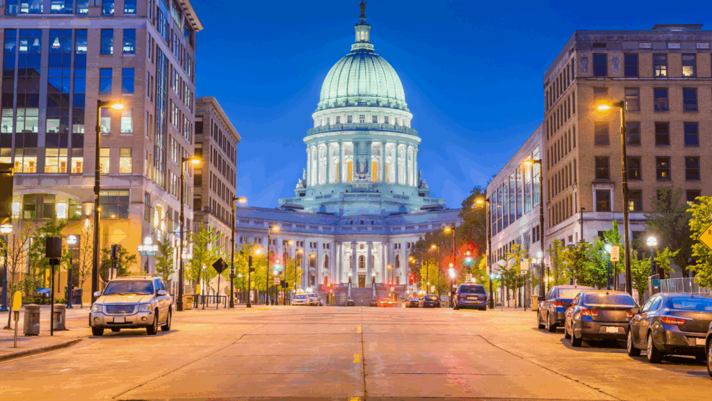 Downtown Madison, Wisconsin at dusk with the Wisconsin State Capitol building illuminated in the background.