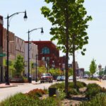 Downtown West Allis street view with shops, trees, and cars on a sunny day.