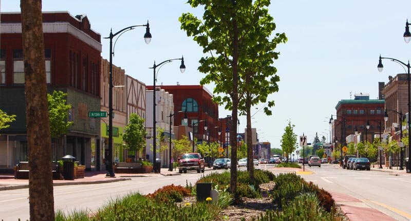 Downtown West Allis street view with shops, trees, and cars on a sunny day.
