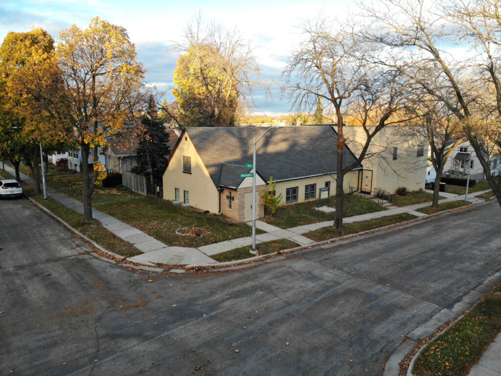 Corner view of a tan house in West Allis with autumn trees and empty streets.
