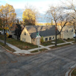 Corner view of a tan house in West Allis with autumn trees and empty streets.