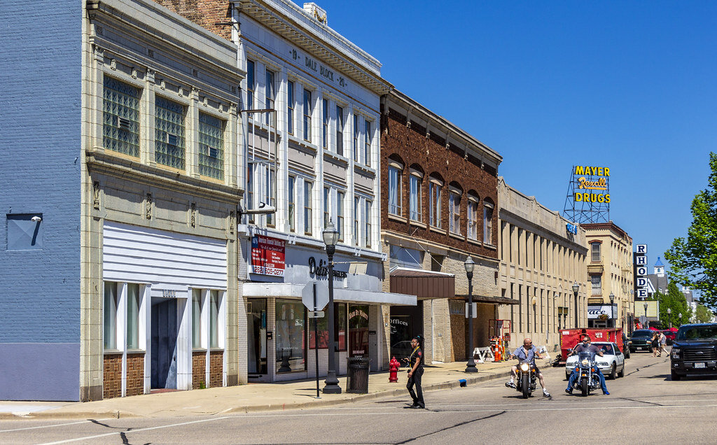 Historic downtown street view in Kenosha, Wisconsin featuring vintage brick buildings, local businesses, and motorcycles on a sunny day — a visual representation of the vibrant community where homeowners often seek opportunities to sell in Kenosha, even if their properties need repairs.