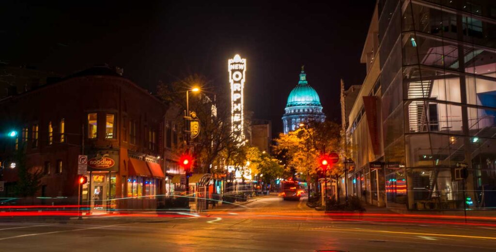 Downtown Madison at night with the Wisconsin State Capitol dome glowing in the background and the Orpheum Theatre sign lit up.