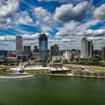 Aerial view of downtown Milwaukee, Wisconsin, with modern skyscrapers, the Milwaukee Art Museum, and Lake Michigan under a partly cloudy sky.