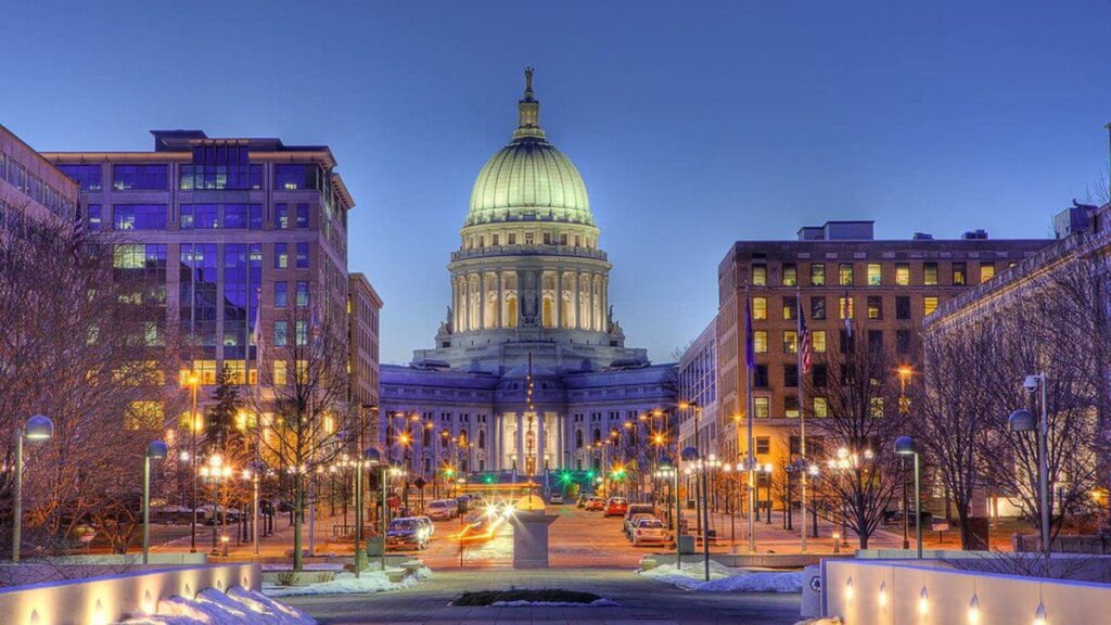 Downtown Madison, Wisconsin at dusk with the Wisconsin State Capitol building lit up in the center.