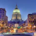 Downtown Madison, Wisconsin at dusk with the Wisconsin State Capitol building lit up in the center.