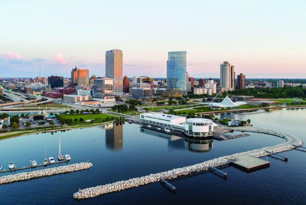 Aerial view of downtown Milwaukee skyline with high-rise buildings and Lake Michigan waterfront.