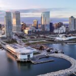 Aerial view of downtown Milwaukee at sunrise, showing modern skyscrapers, the Milwaukee Art Museum, and Lake Michigan’s waterfront.