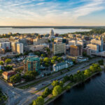 Aerial view of downtown Madison, Wisconsin, featuring the Capitol building, lakes, and surrounding neighborhoods.