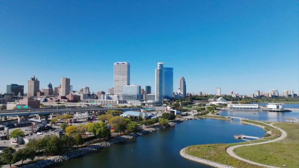 Aerial view of downtown Milwaukee skyline overlooking Lake Michigan on a clear blue day.