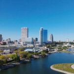 Aerial view of downtown Milwaukee skyline overlooking Lake Michigan on a clear blue day.