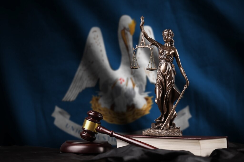 Louisiana US state flag with statue of lady justice, constitution and judge hammer on black drapery. Concept of judgement and guilt