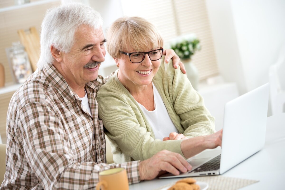 Happy elderly couple have fun at home with a laptop