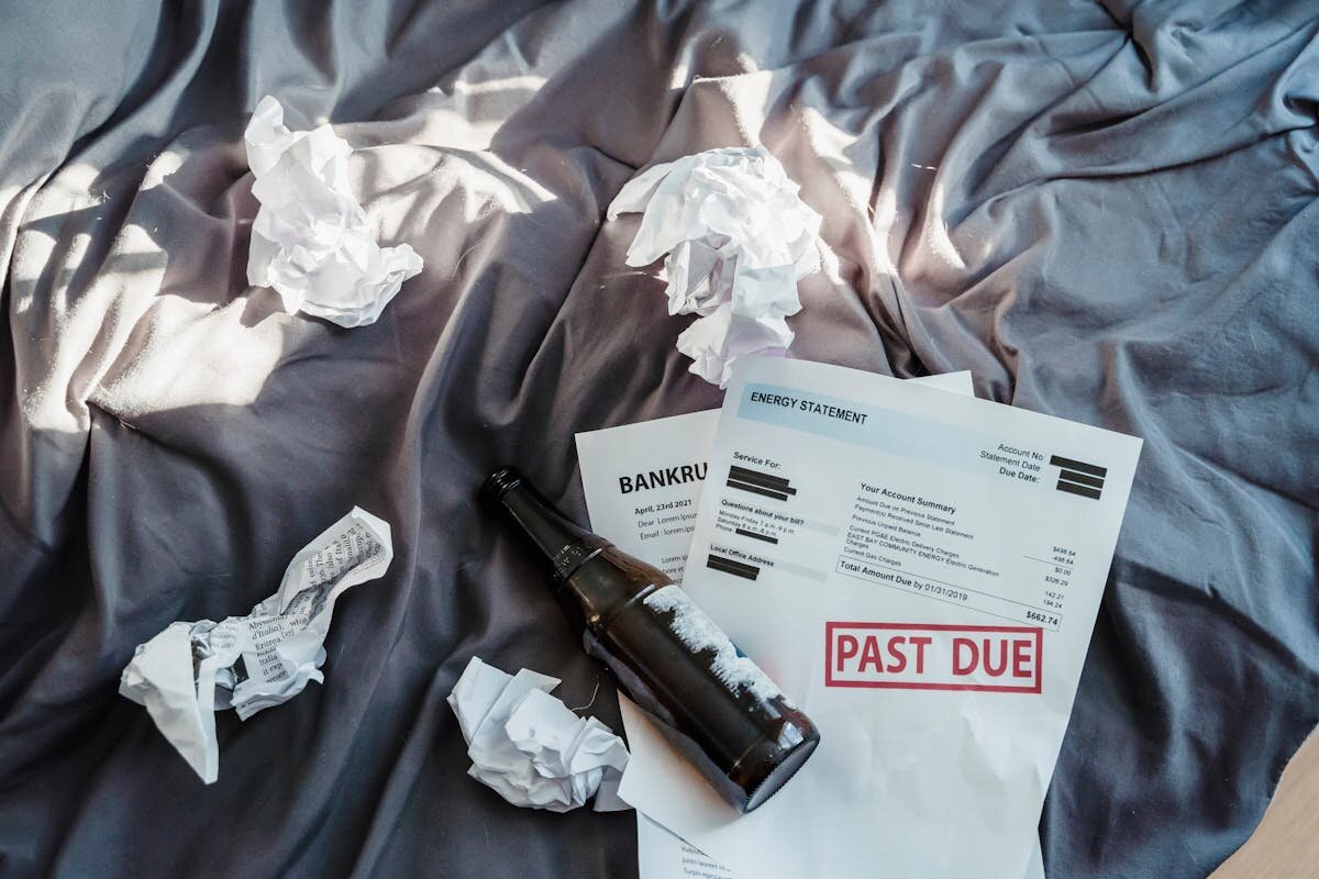 a picture of a bunch of past due bills on a bed with crumpled up paper next to it for buying a house