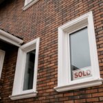 a brick house with a sold sign in the window